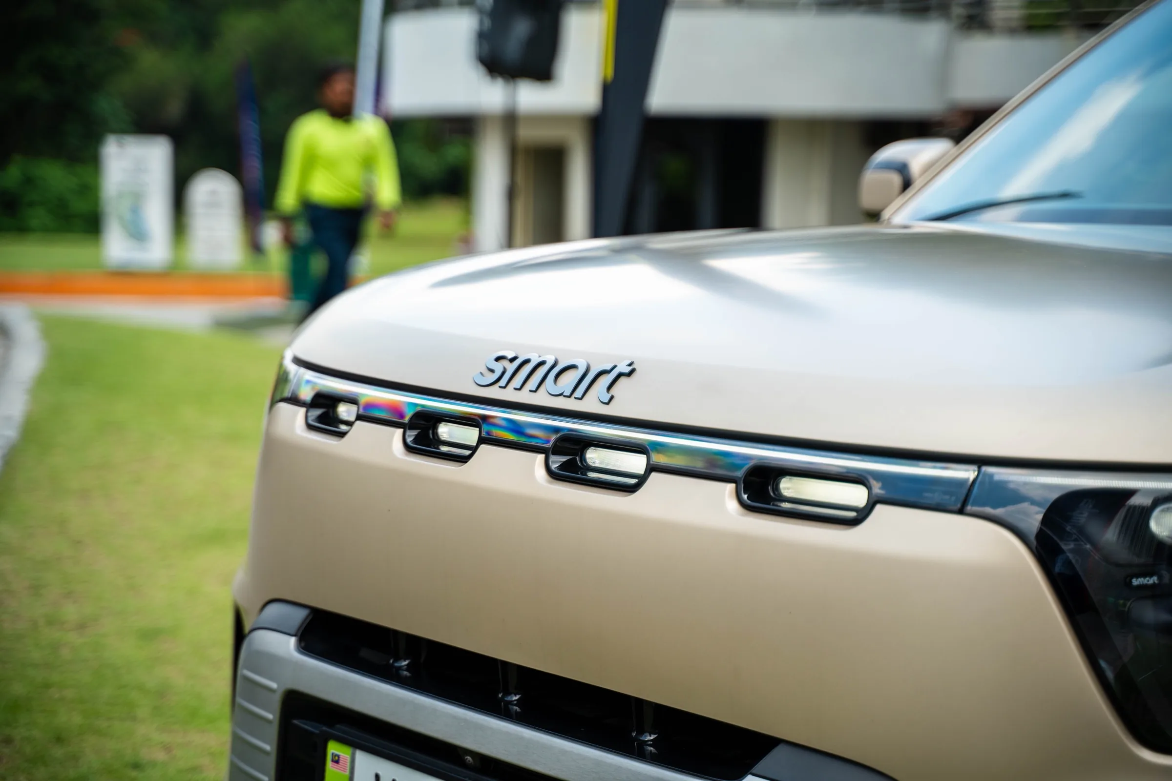 Close-up photo of the front exterior of a smart brand car, focusing on the chrome smart logo and front light bar.