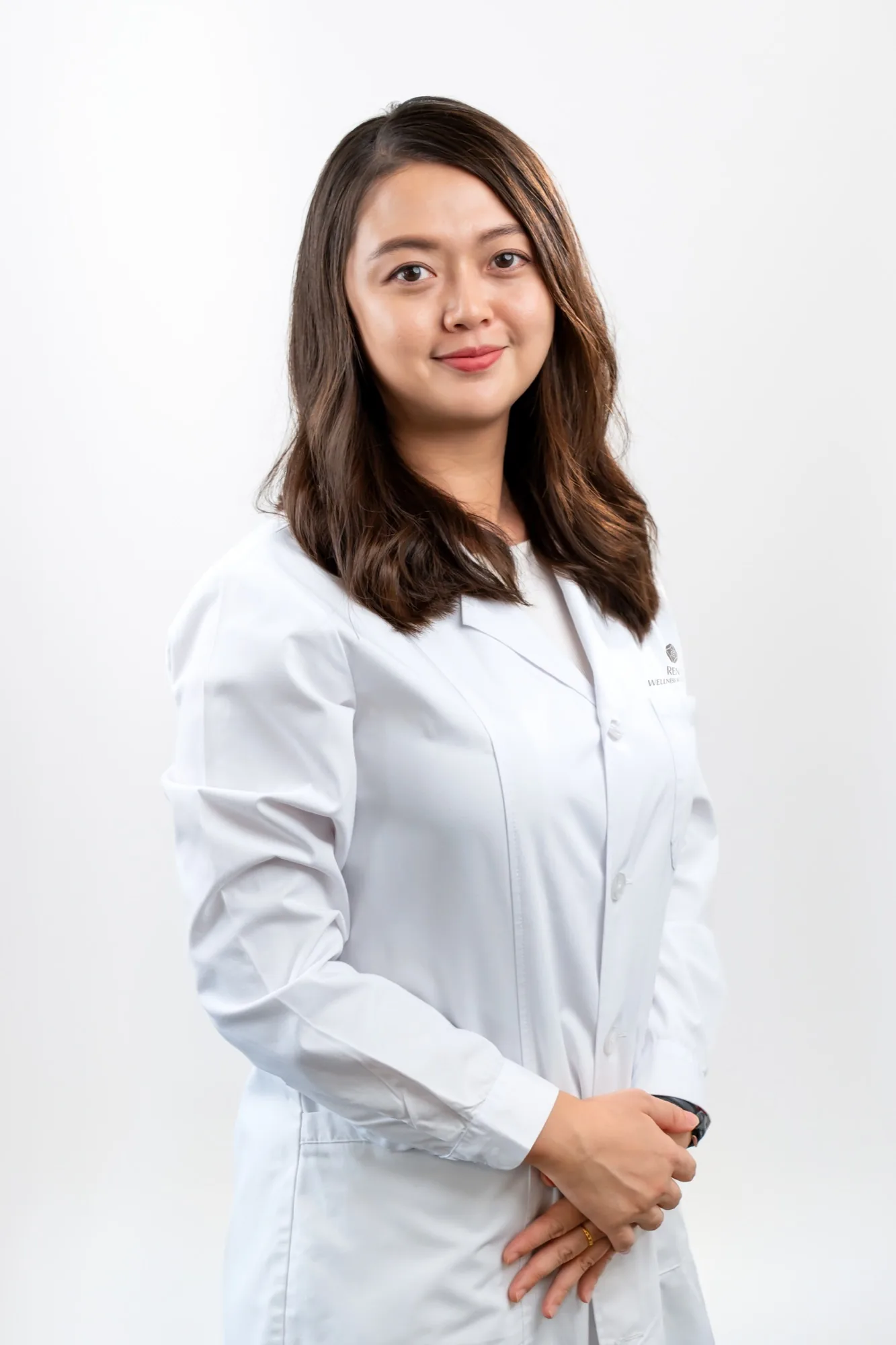 Professional portrait of a Ren Wellness Retreat TCM practitioner wearing a white clinical coat against a clean studio background.